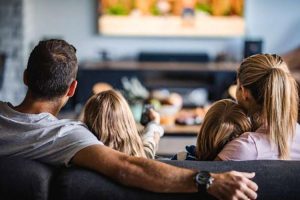 Familia viendo una película en el living de su hogar.
